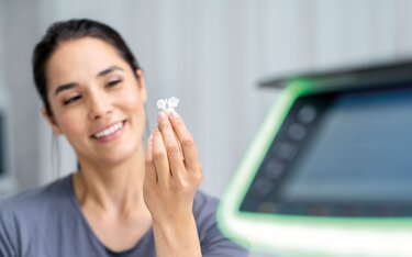 Female dentist looking at an Ivoclar dental restoration created using Press Technology.